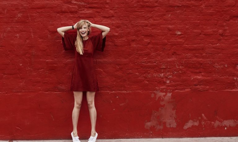 Junge Frau in rotem Kleid vor roter Wand