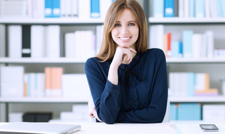 Frau am Schreibtisch mit dunkelblauer Bluse